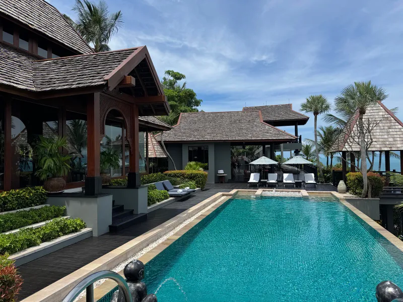 Longue piscine à débordement avec toits en bois de style thaï et transats au Four Seasons Resort Koh Samui