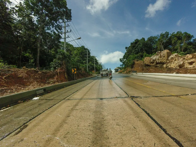 Quiet two-lane hillside road with power lines and jungle on both sides, near Koh Samui's Laem Yai headland