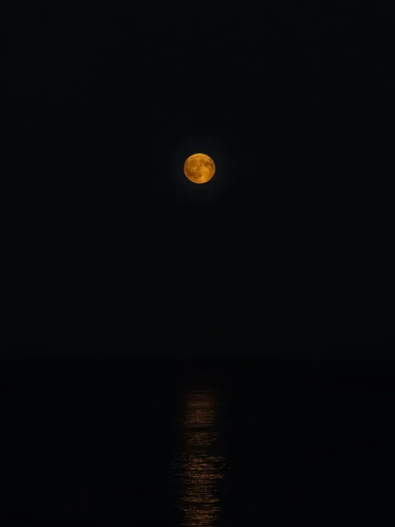 Golden full moon reflecting on the Gulf of Thailand at night near Koh Samui and Koh Phangan