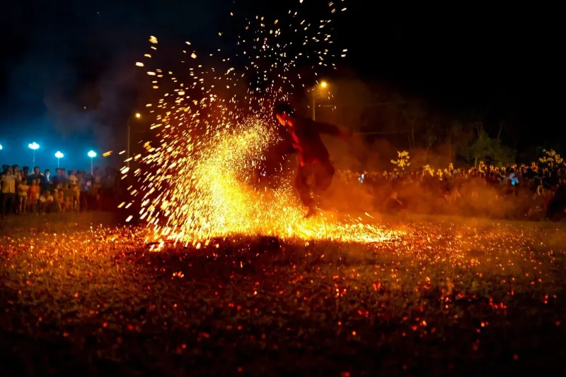 Fire dancer performing with sparks at a crowded night event, the style of act found at Haad Rin's beach parties