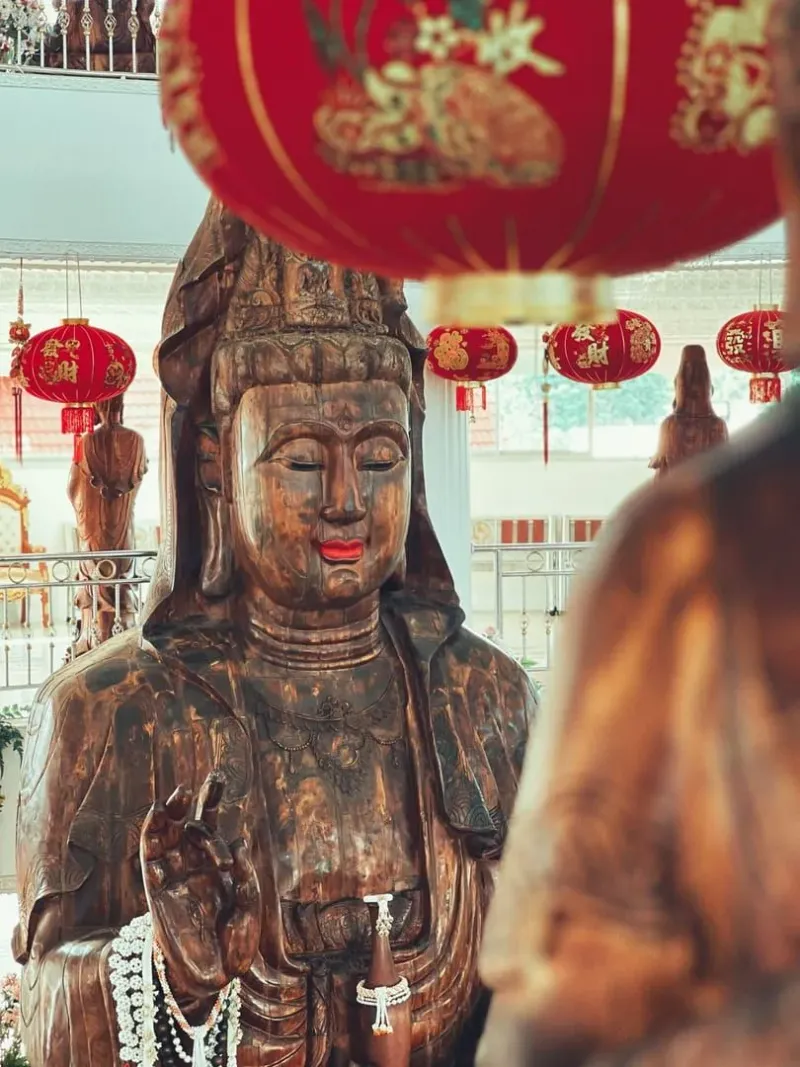 Guan-Yin-Statue zwischen roten Laternen in einem thailändischen Tempel
