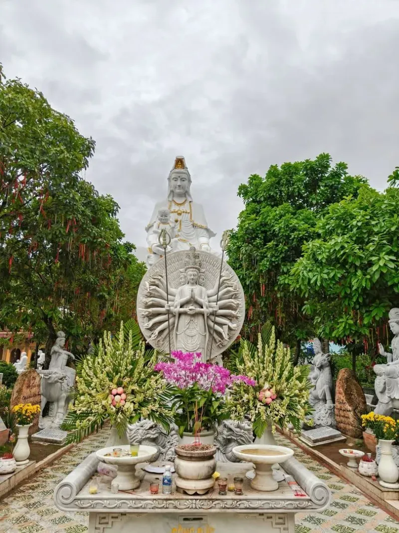 Guan-Yin-Statue umgeben von Grün und Blumen in Bình Ninh, Vietnam