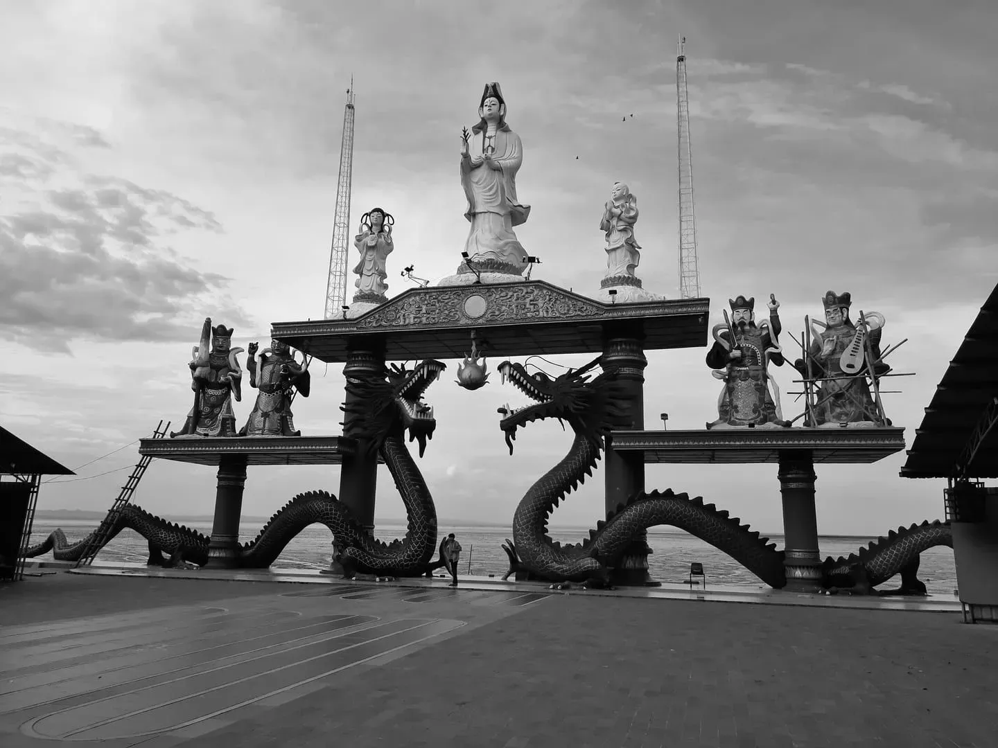 Schwarz-weiß-Foto einer Guan-Yin-Statue umgeben von Drachenskulpturen in Surabaya, Indonesien