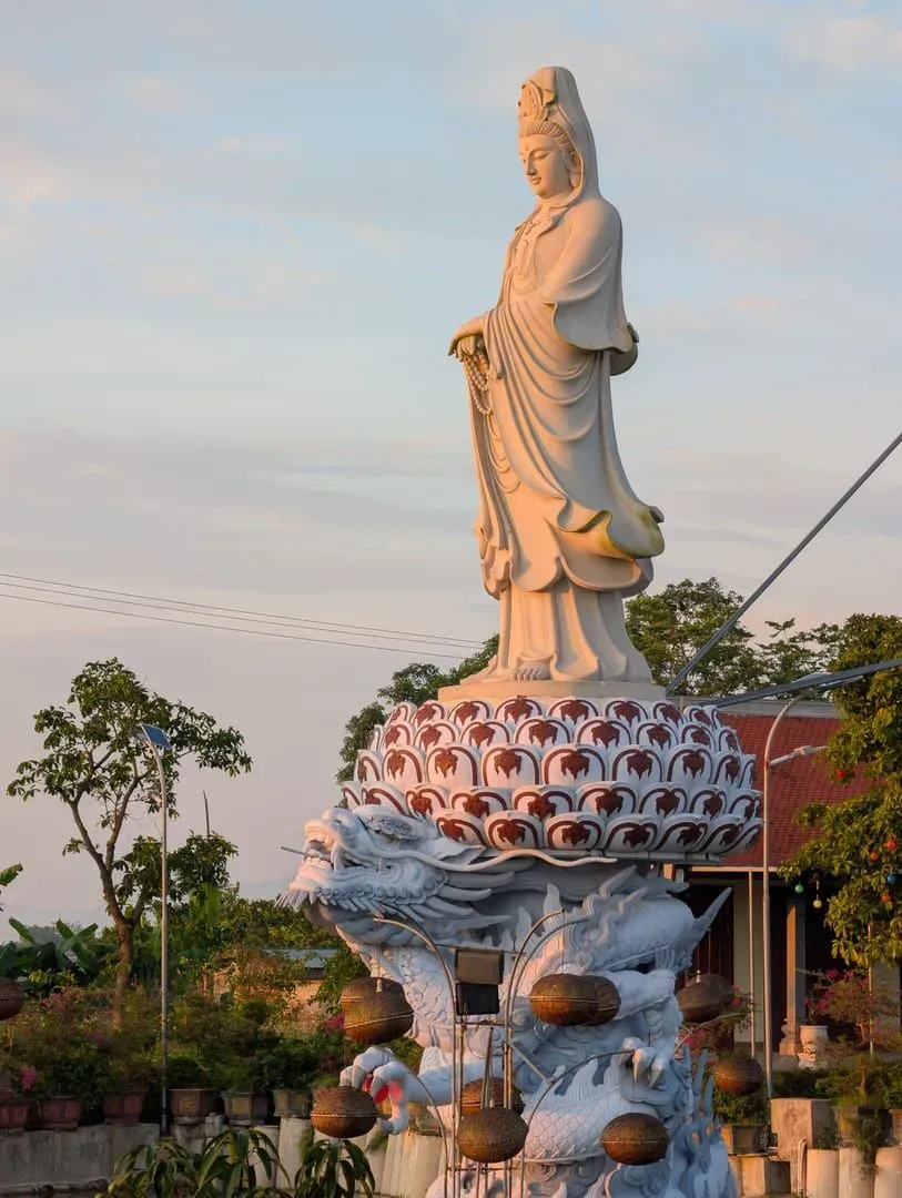 Weiße Guanyin-Statue auf einer Lotosblüte bei Sonnenaufgang