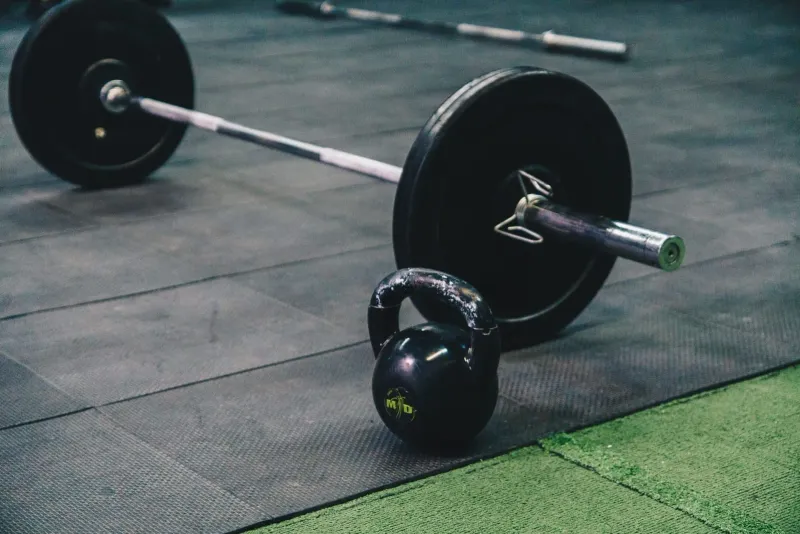 Barre et kettlebell posées sur le sol d'une salle de sport, le matériel de préparation physique que BXB Fight Lab énumère sur sa page des installations