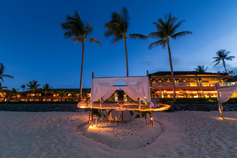Cena in spiaggia a lume di candela con un baldacchino sulla sabbia davanti al ristorante dell'Hansar Samui al crepuscolo