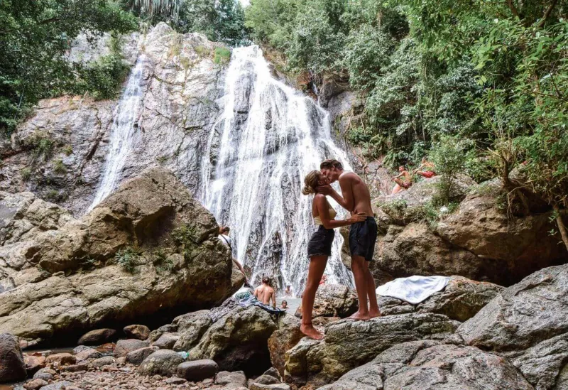 Besucher rasten auf den Felsen rund um Hin Lads Hauptbecken