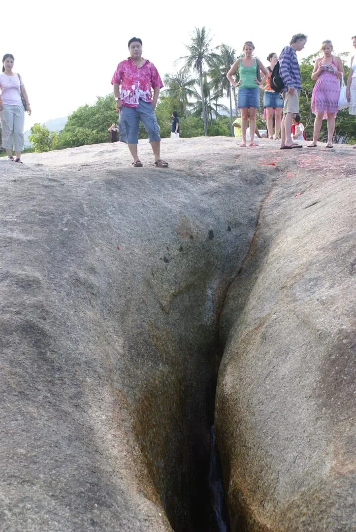 Close-up of Hin Yai, the cleft grandmother rock, with visitors standing on the granite outcrop at Lamai Beach