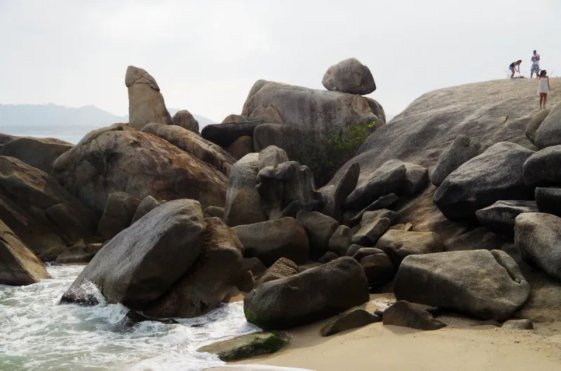 Visitors climbing over the granite boulders at Hin Ta Hin Yai, with Hin Ta visible in the background