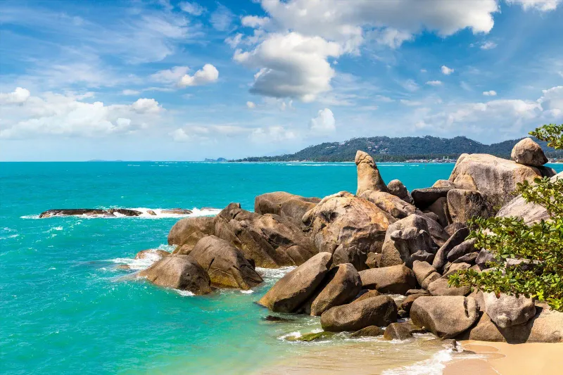 Hin Ta standing above the boulder field with turquoise water and Lamai's coastline in the background