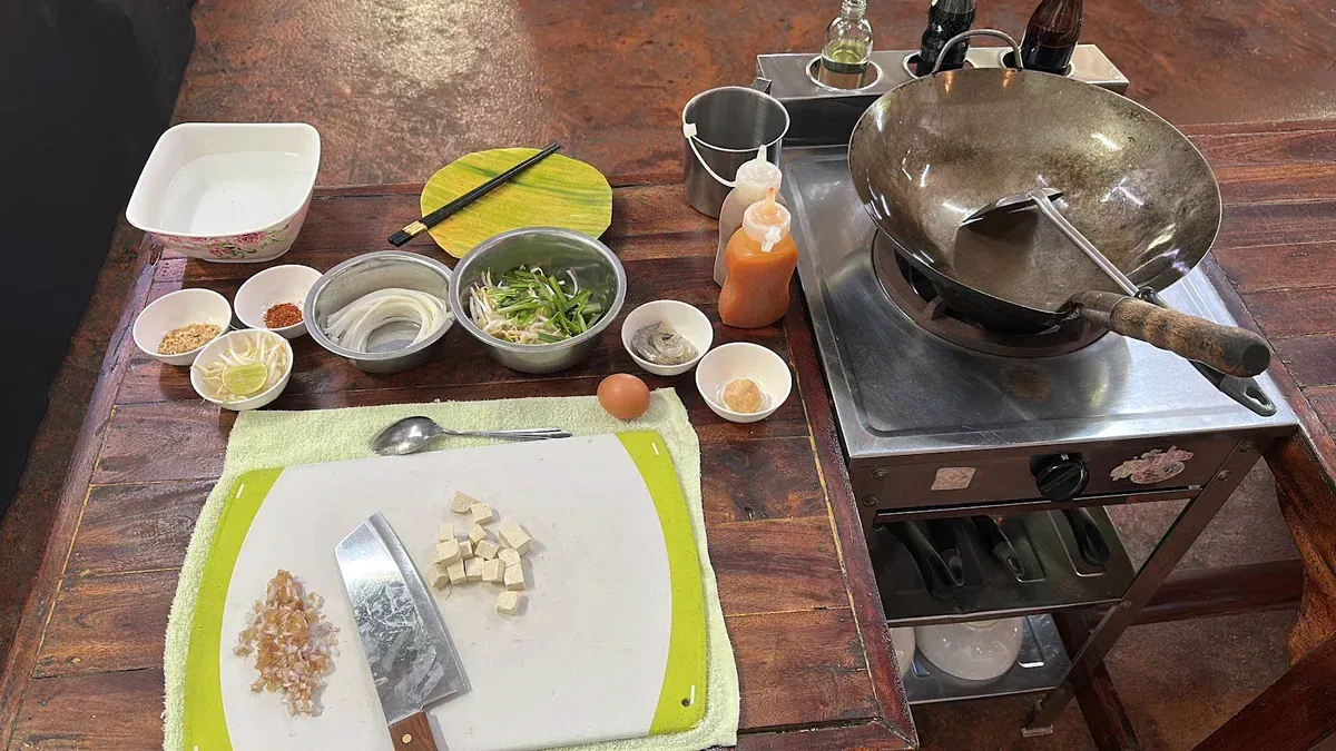 A prep station with wok, chopped ingredients and condiments set out for an Island Organics Samui cooking class