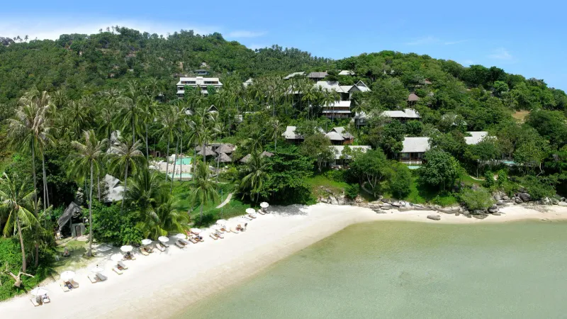 Veduta aerea dei bungalow del Kamalaya Koh Samui tra le palme sopra la baia di sabbia privata a Laem Set