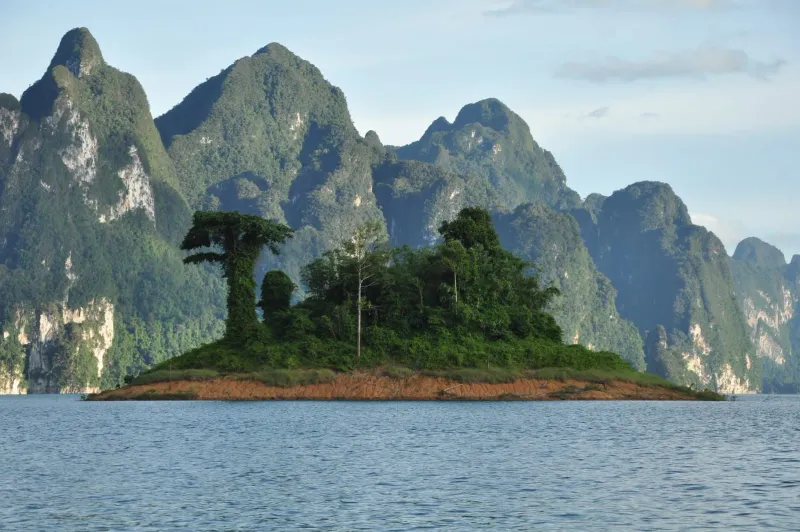 Small forested island rising from the calm waters of Cheow Lan Lake near Khao Sok