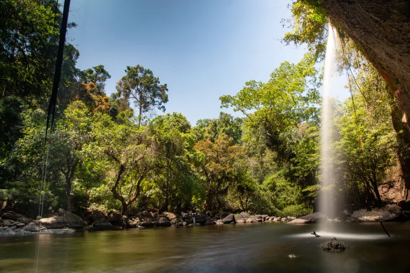 Ein Dschungelwasserfall, der in ein ruhiges Flussbecken unter einem überhängenden Felsvorsprung auf Koh Samui fällt