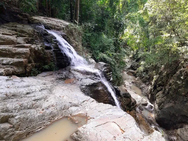 Eine abgestufte Kaskade an Khun Si fließt über Granitgestein
