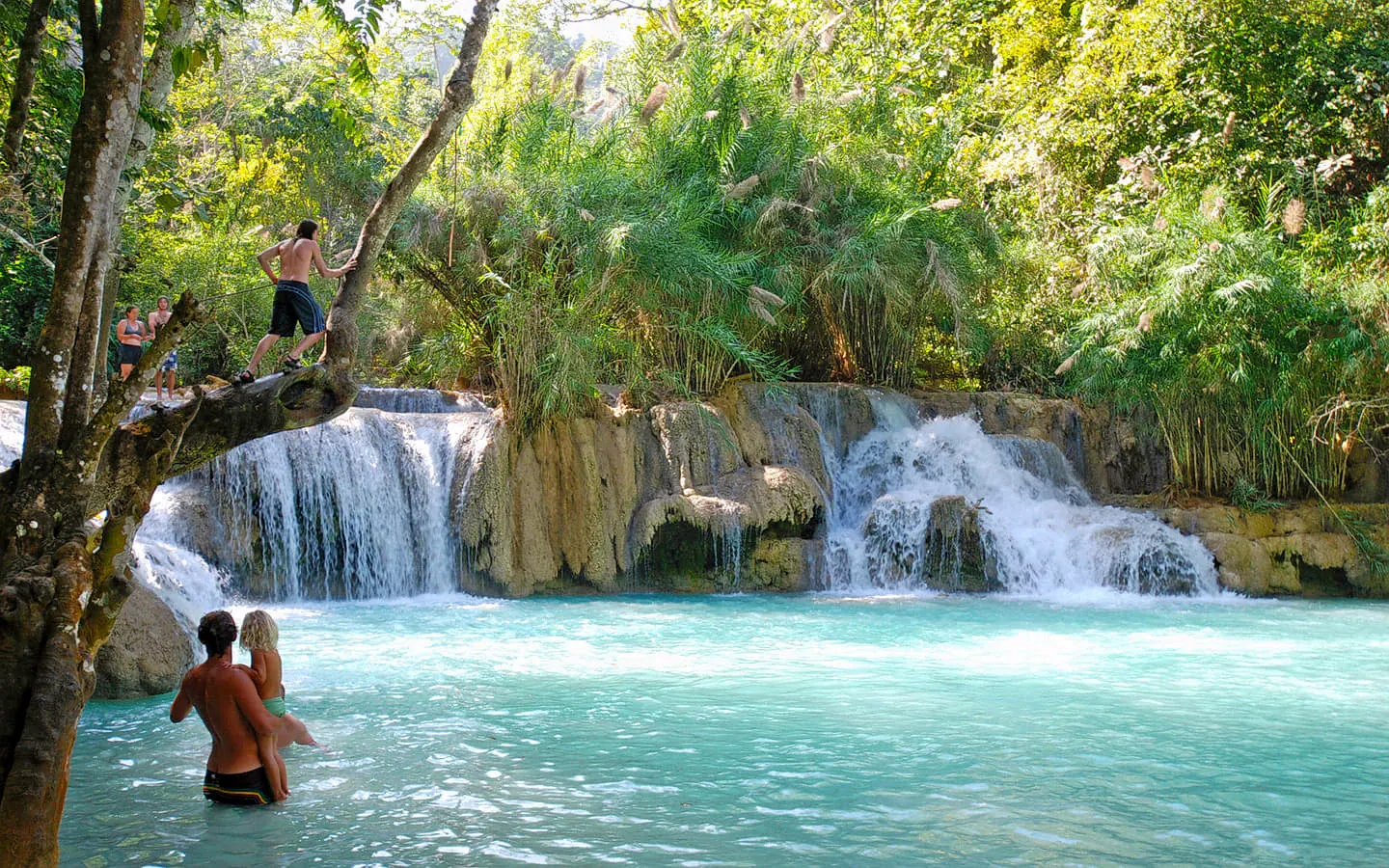 La luz del sol capta la espuma en la piscina principal de la Cascada Khun Si