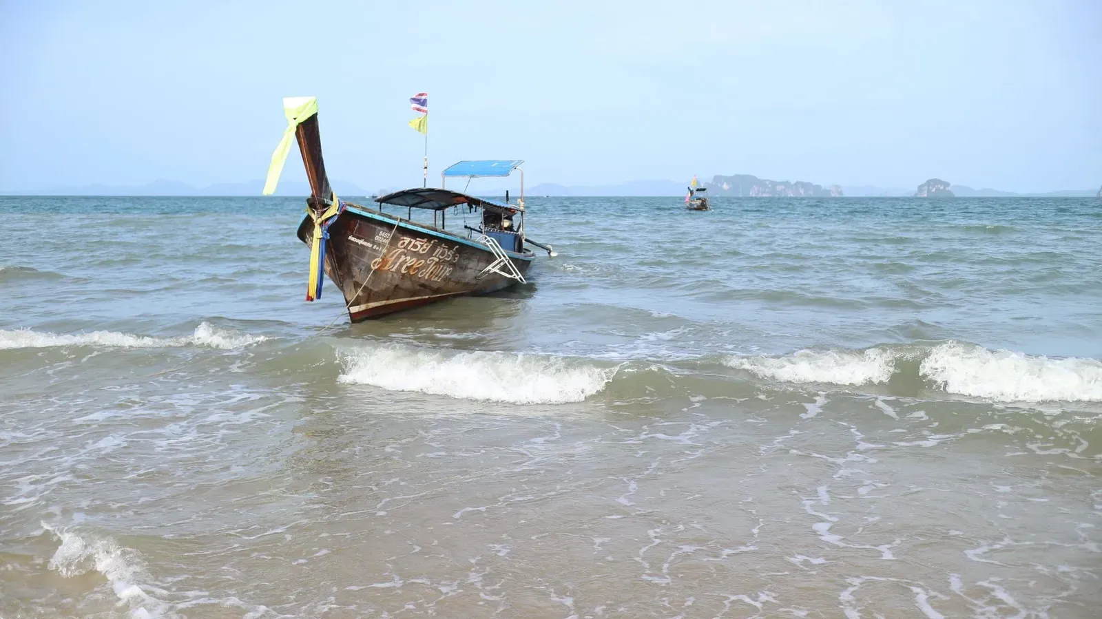 Traditional longtail boat resting on a quiet beach on Thailand's Andaman coast
