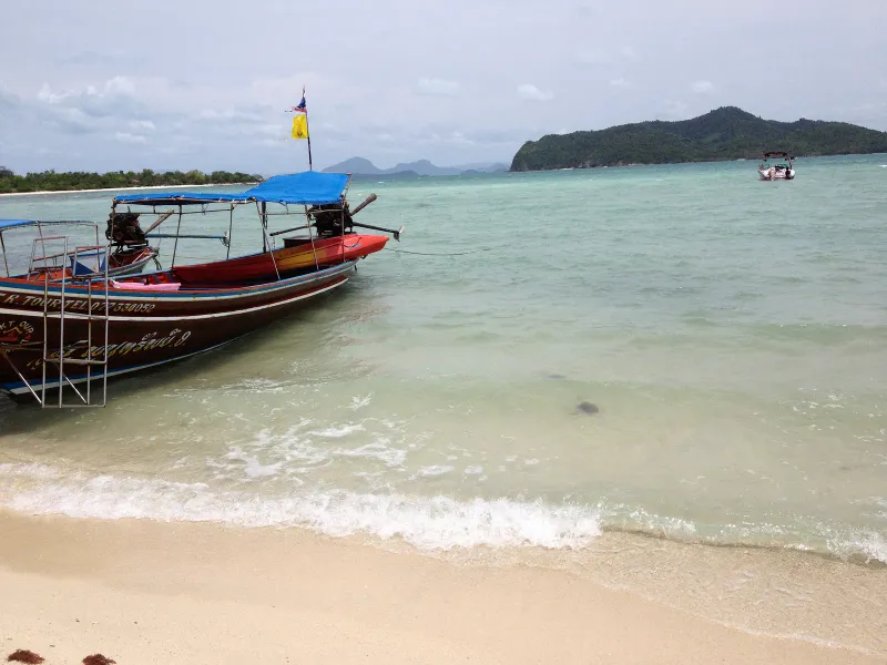 Un longtail varado en la arena de Koh Madsum, con agua somera y cristalina alrededor