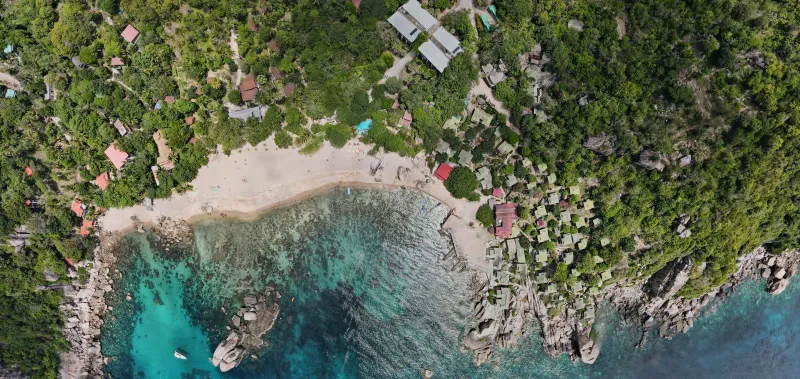 Tropical beach with lush greenery and clear blue water near a Koh Tao snorkeling stop