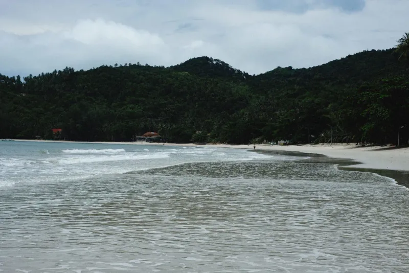 Coastal scene with green hills and sandy shore along the Koh Phangan day trip route