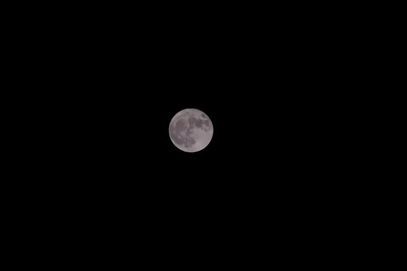 Full moon glowing in a clear night sky over open water, the lunar cycle that sets each Full Moon Party date