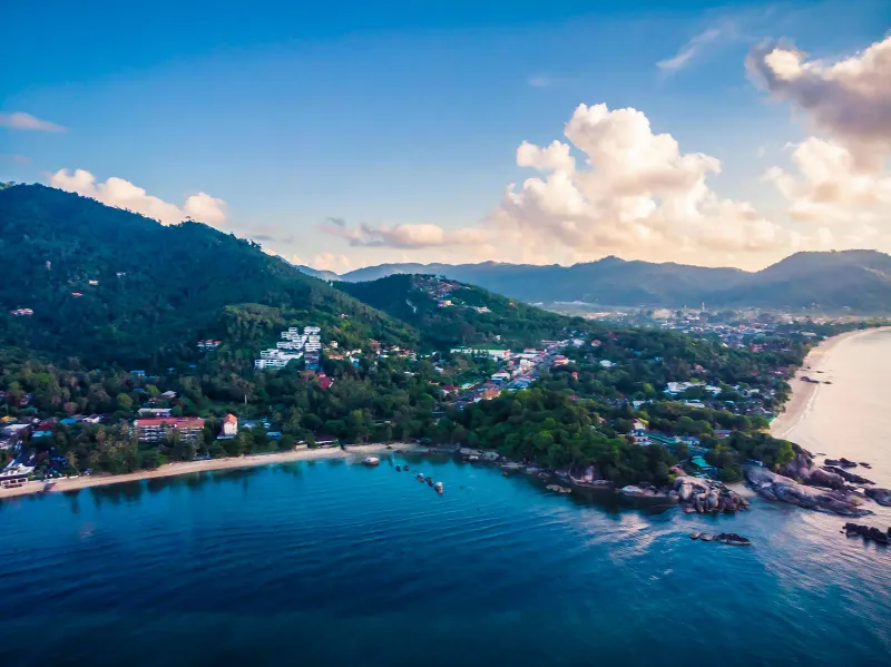 Vue aérienne d'une côte montagneuse de Koh Samui avec baie, rochers et maisons près de Lamai sous des nuages de coucher de soleil