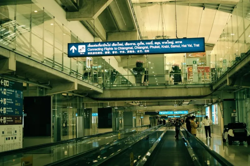 Airport moving walkway with signage for connecting flights to Koh Samui