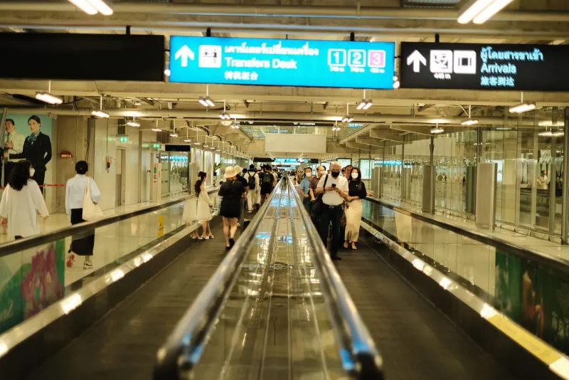 Passeggeri che attraversano l'area arrivi di un aeroporto prima di raggiungere il punto di ritiro delle app di trasporto