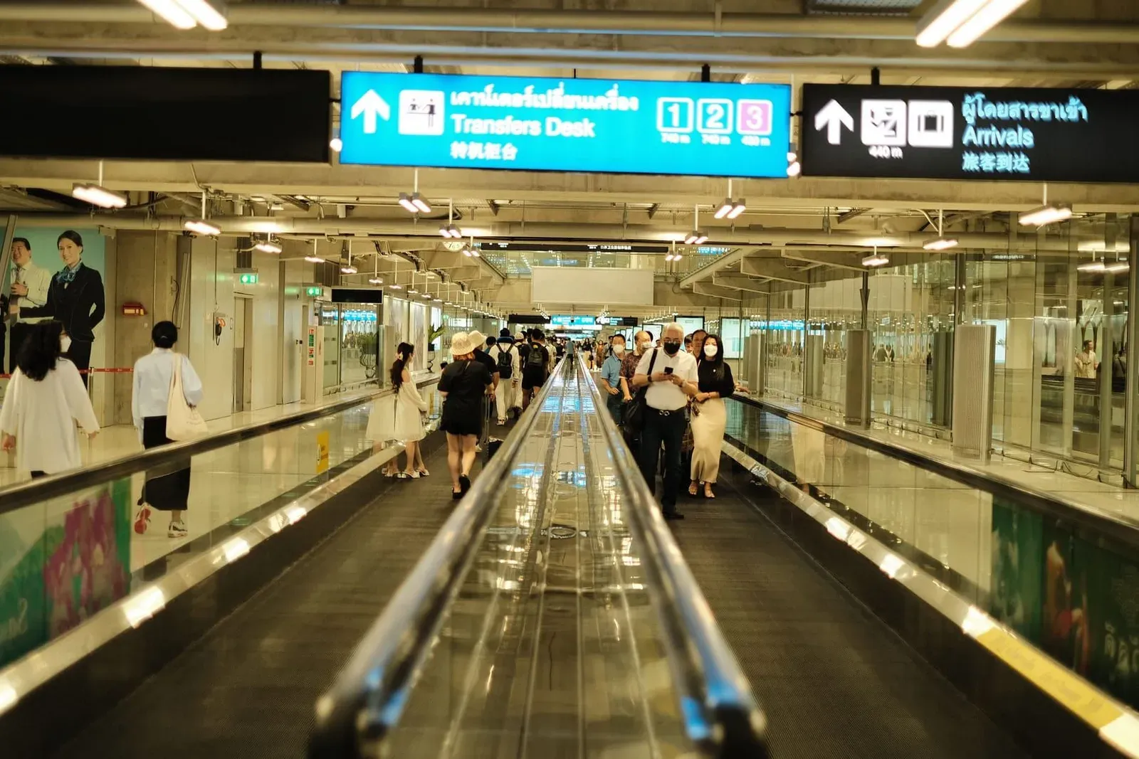 Passengers walking through the arrivals area at an airport before heading to a ride-hailing pickup point