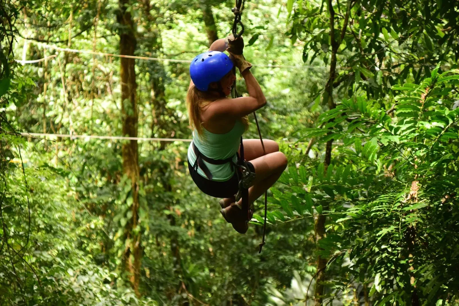 Woman on a zipline moving through dense green forest canopy, similar to Koh Samui's jungle zipline parks