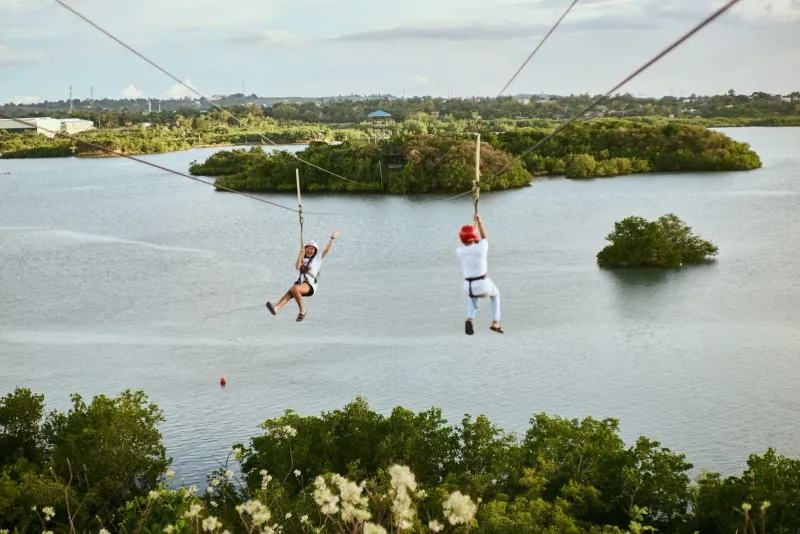 Zipline rider gliding over water and greenery similar to Koh Samui canopy tours