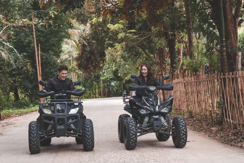 Due persone su quad che attraversano un terreno rurale in un tour in ATV in stile Koh Samui