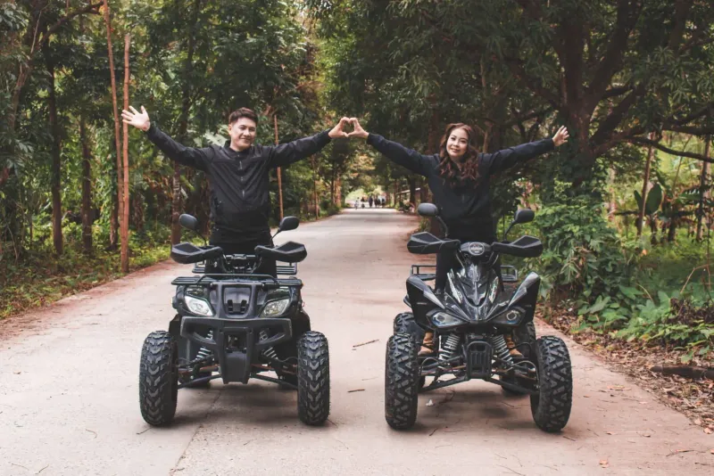 Couple riding quad bikes together on a forest road on a Koh Samui-style ATV tour