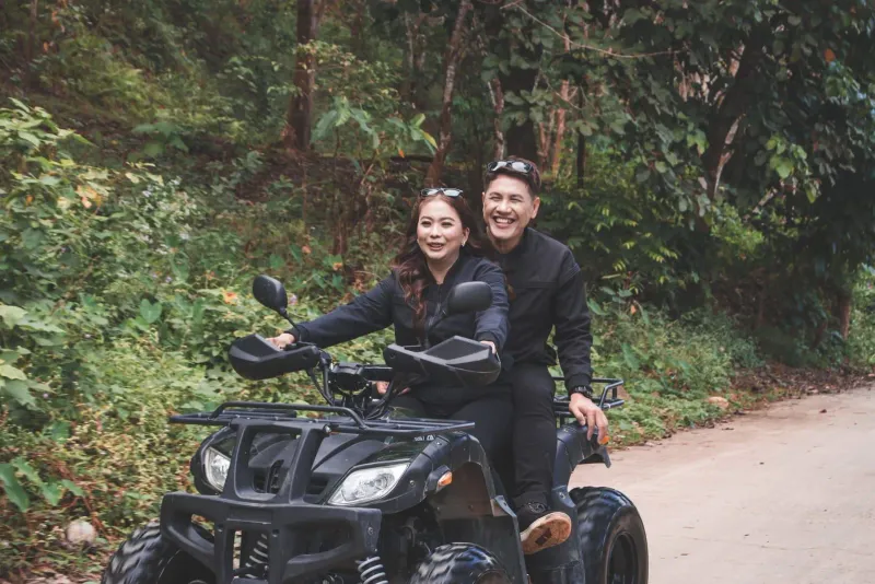 Smiling riders on a quad bike touring forest terrain near a Koh Samui adventure park