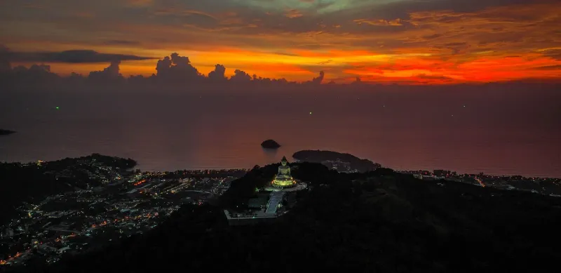 Golden Buddha statue on a hillside at sunset, similar in style to Koh Samui's Big Buddha landmark