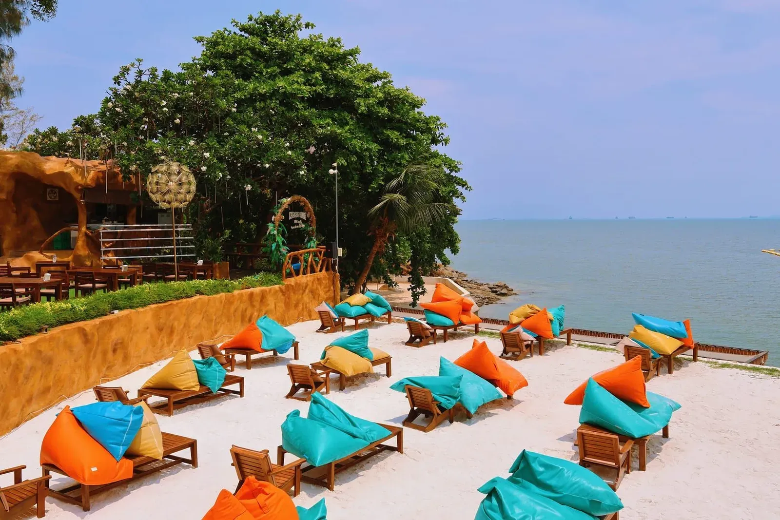 Colorful beach loungers beside turquoise water at a Koh Samui beach club by day