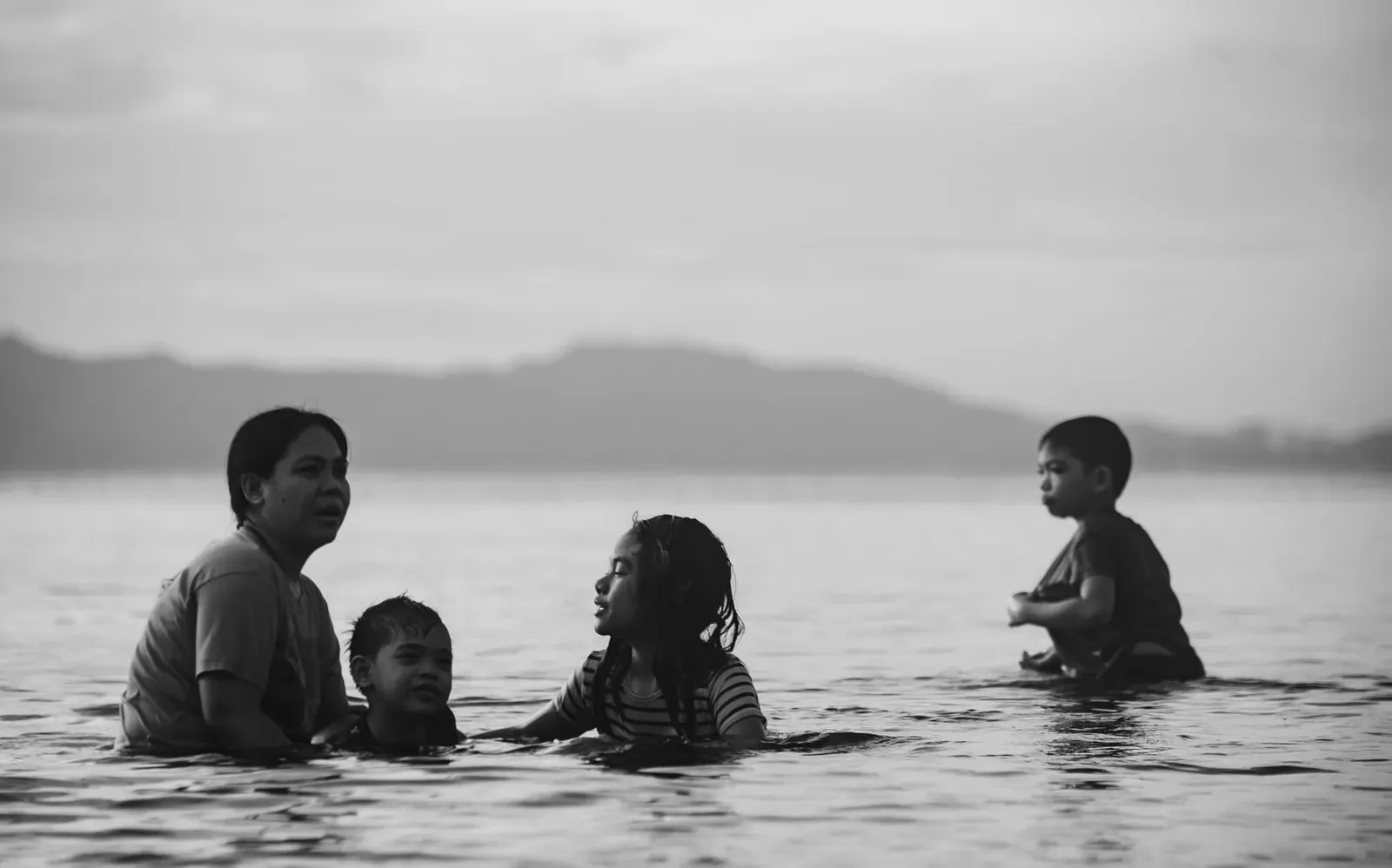 Mother and children swimming together in shallow water on a Koh Samui beach