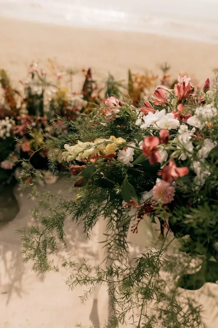 Floral arrangement laid out on the sand for a beach wedding decor display