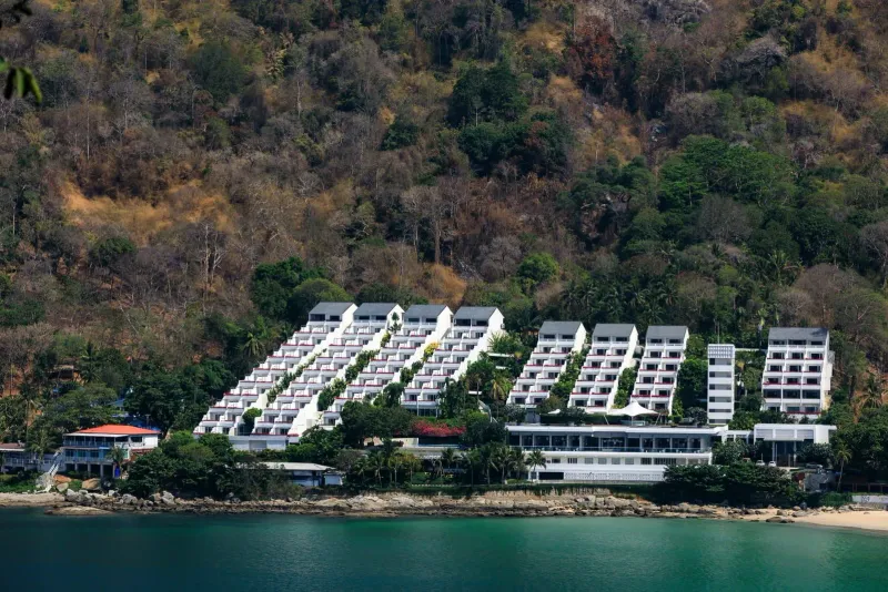 Modern white resort buildings on a lush tropical coastline near the beach
