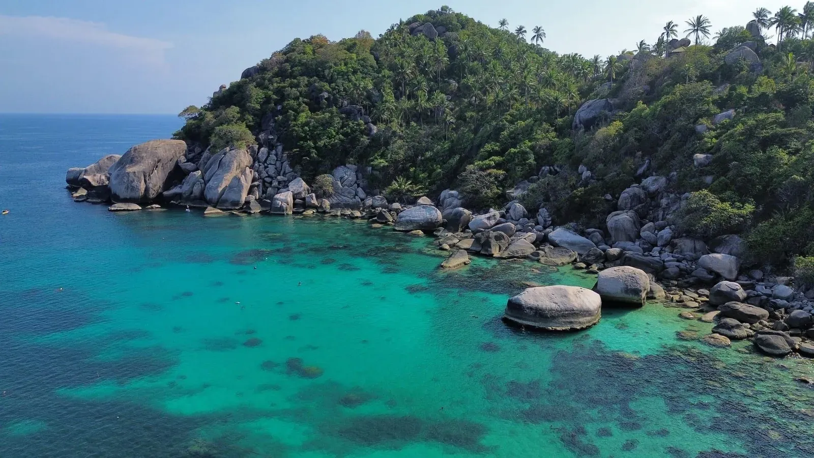 Aerial shot of a tropical bay with turquoise water and lush greenery similar to Koh Samui's north coast