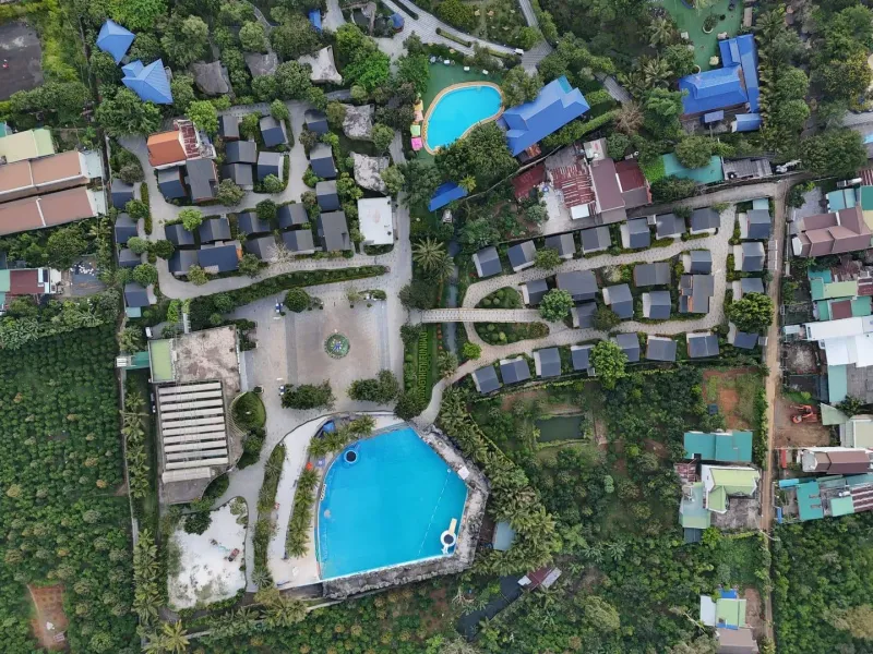 Aerial view of a lush boutique resort with blue pools and villas on Koh Samui's north coast