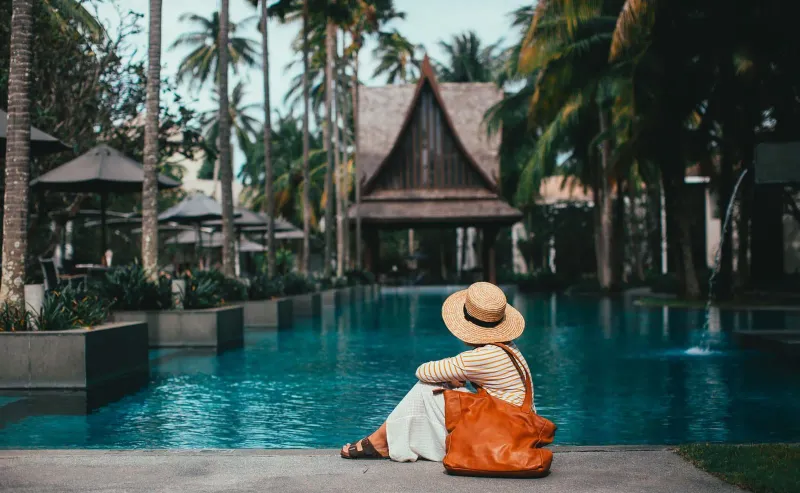 Guest relaxing poolside at a quiet Koh Samui boutique resort surrounded by palms and bungalows