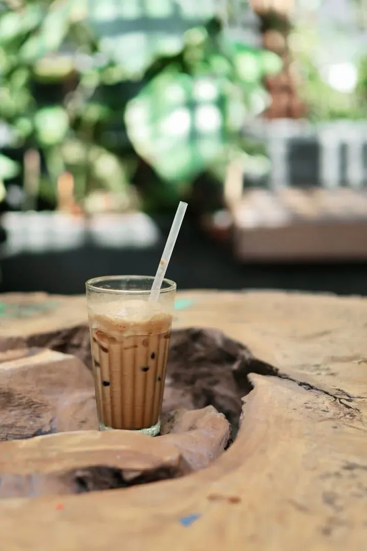 Iced coffee on a rustic wooden table at a sunlit Koh Samui cafe terrace