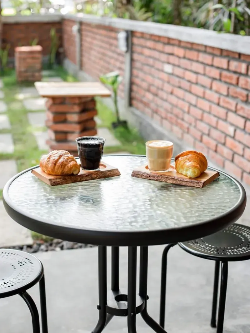 Coffee and croissants on a glass table at an outdoor café, a typical Koh Samui specialty coffee setting