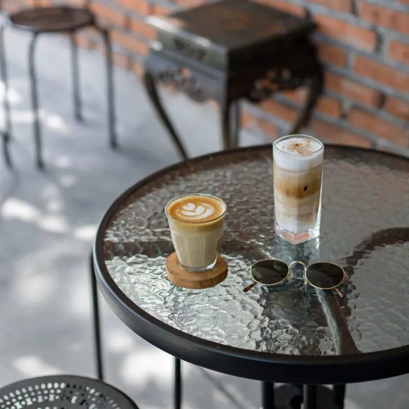 Lattes and sunglasses on a glass table at a Fisherman's Village style Koh Samui cafe