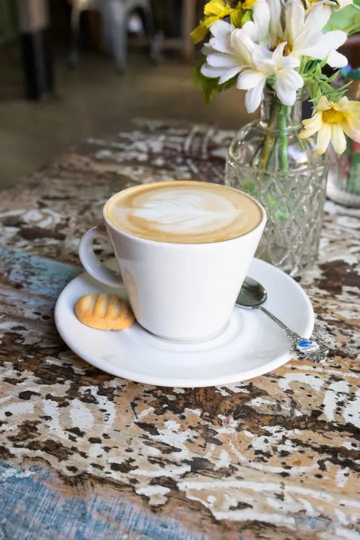 Latte with a biscuit on a rustic table, a cozy Koh Samui cafe atmosphere
