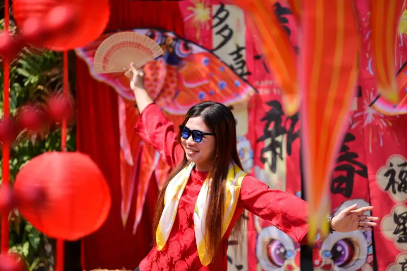 Woman celebrating Chinese New Year outdoors with red decorations and traditional attire