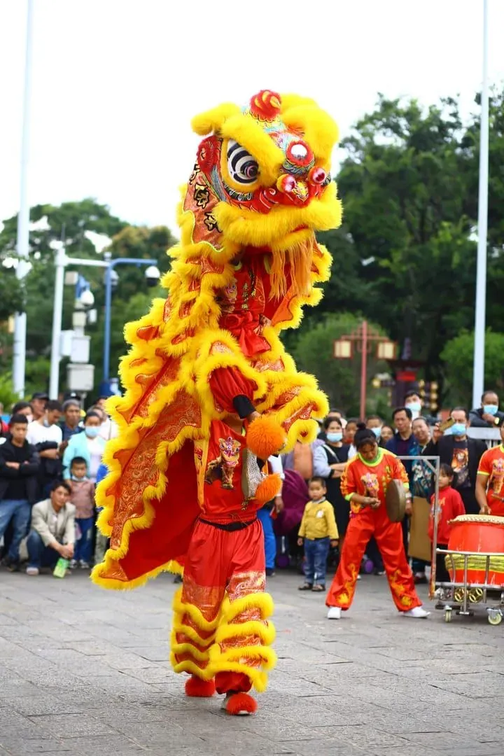 Person in yellow dragon costume performing a dragon dance outdoors