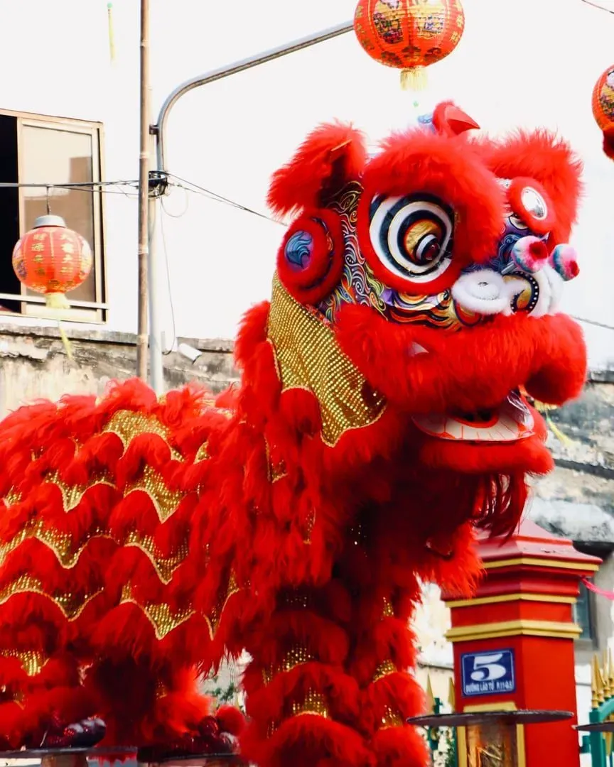Lion dance performance with red lanterns decorating the background during a festival celebration