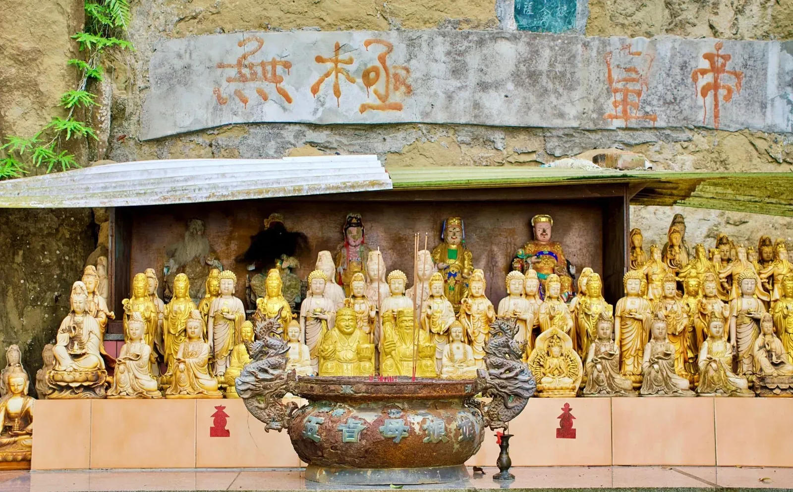 Golden Chinese deity statues and calligraphy inside a temple altar, the interior style found at Samui's Hainanese shrines